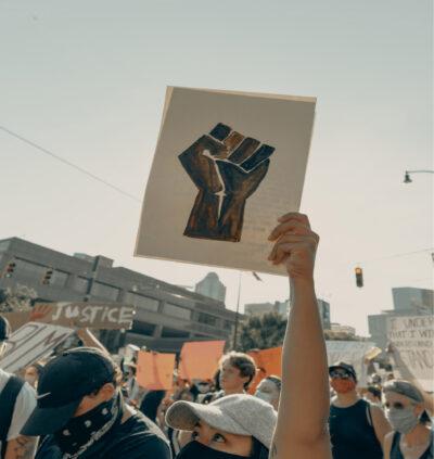 a man holding up a picture of a black fist