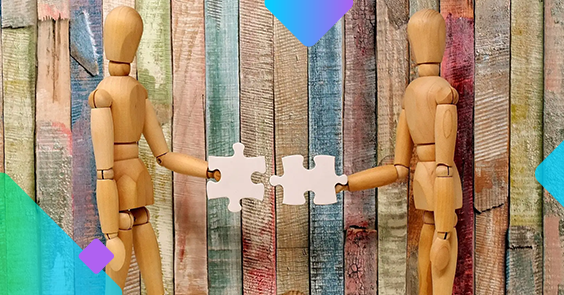 two wooden people models putting two pieces of a puzzle together