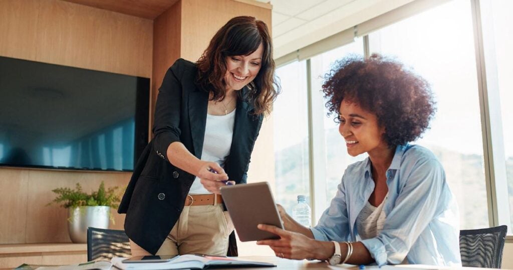 two women pointing at a tablet and smiling