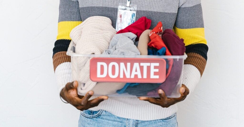 someone holding a bin of clothes thats labeled donate