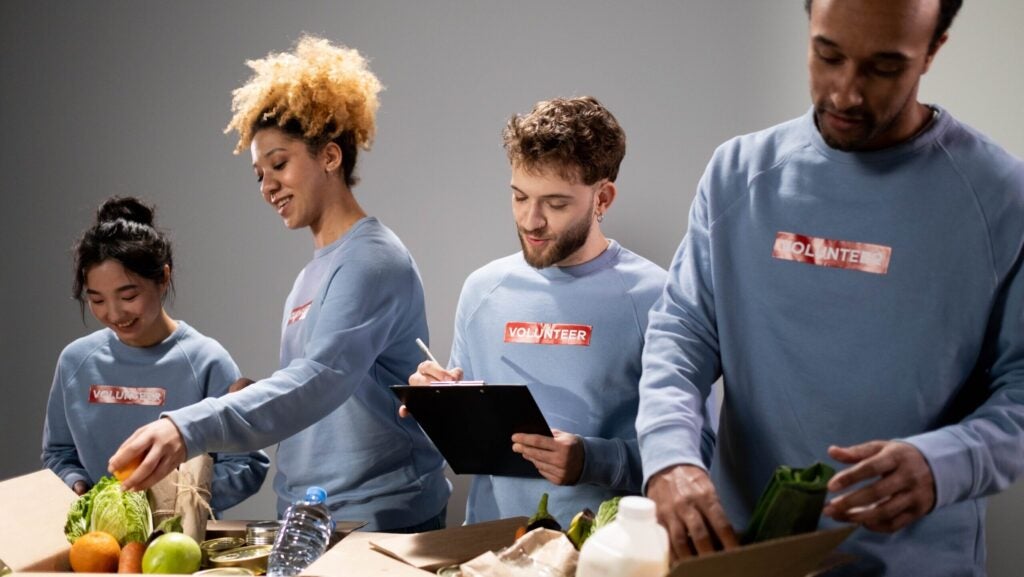 people packing food with volunteer stickers on their matching sweatshirts