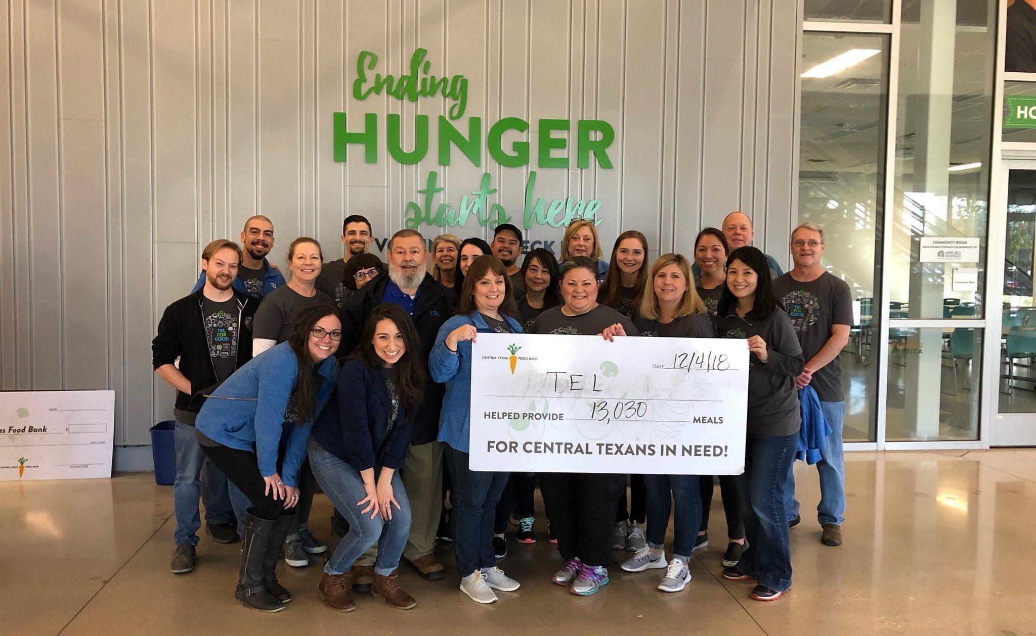 TEL employees holding a sign saying they helped provide 13,030 meal for central texans in need