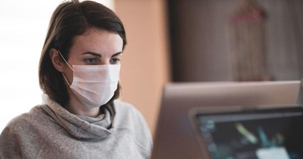 a woman on the computer wearing a covid mask