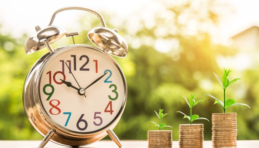 a clock next to three stacks of coins growing plants from the top of them