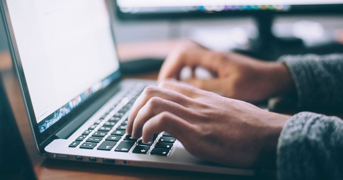 hands typing on a macbook