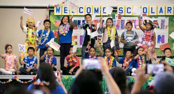 elementary school kids standing on stage waving flags