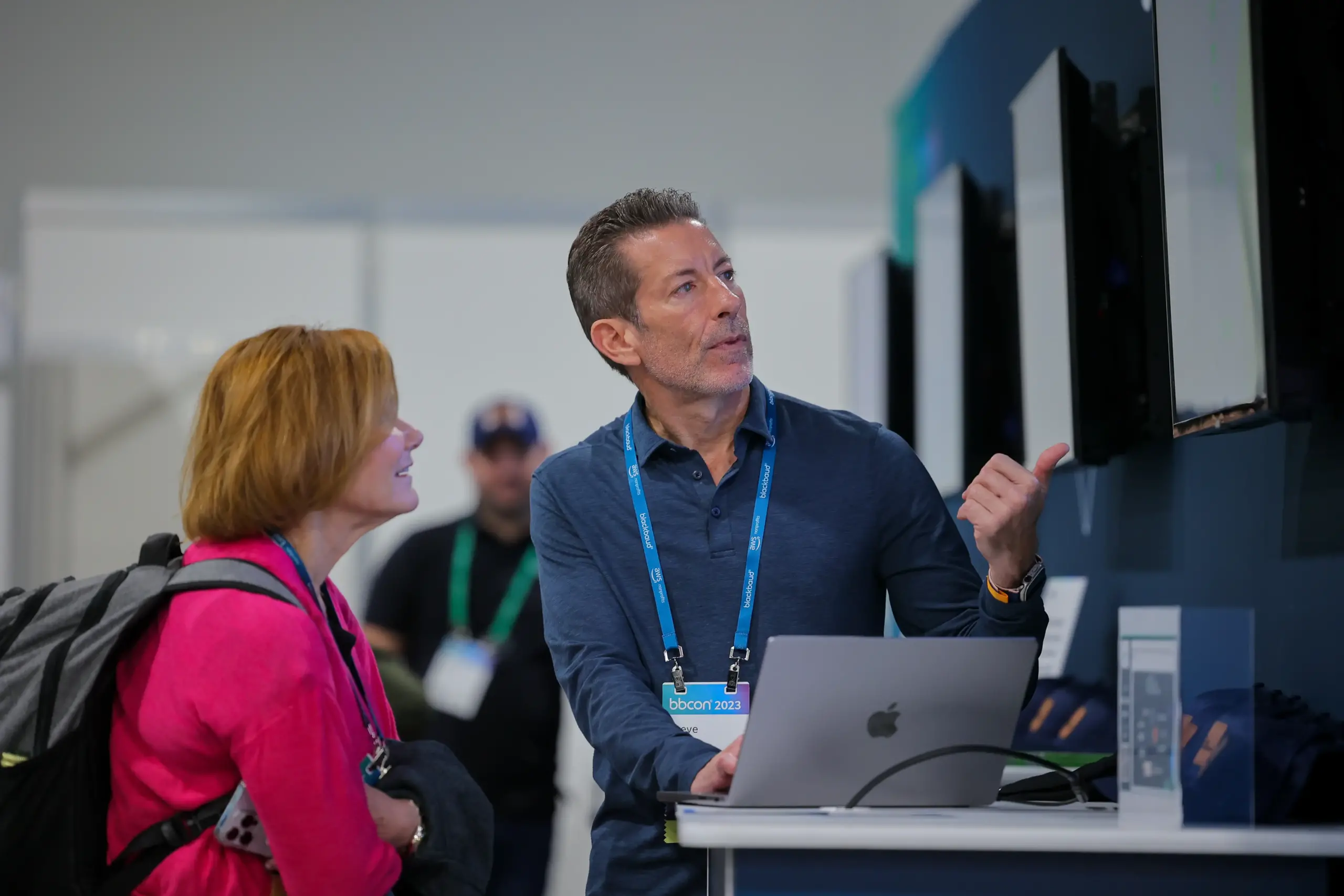 an employee at bbcon 2023 pointing out something at a monitor to an attendee