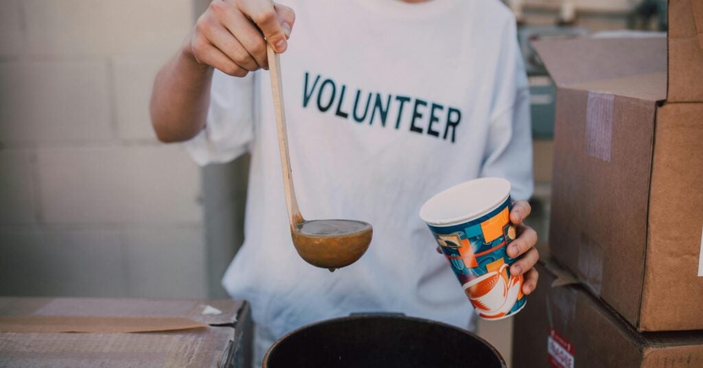 volunteer pouring sour in a cup